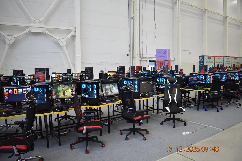 Изображение игрового зала с компьютерами и игровыми креслами.