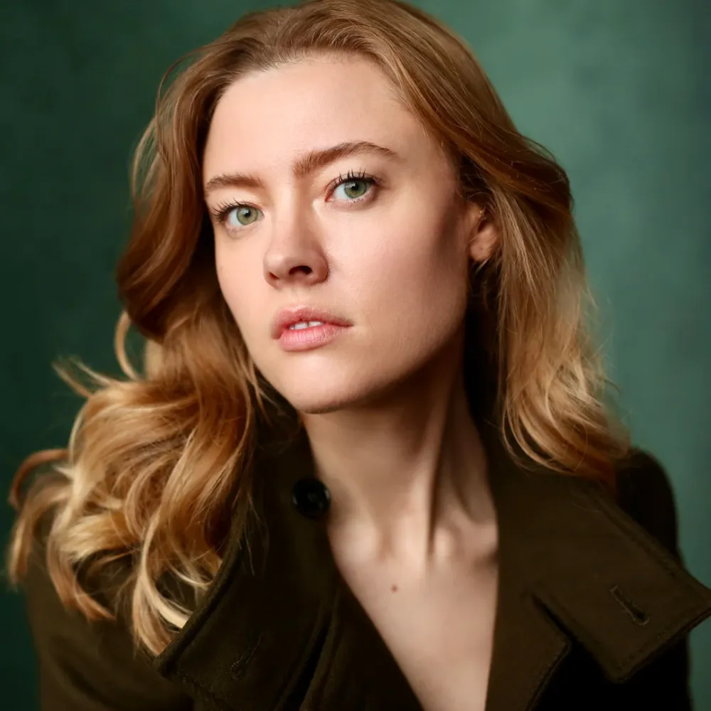 Портрет человека с длинными светлыми волосами, на фоне зеленого цвета.