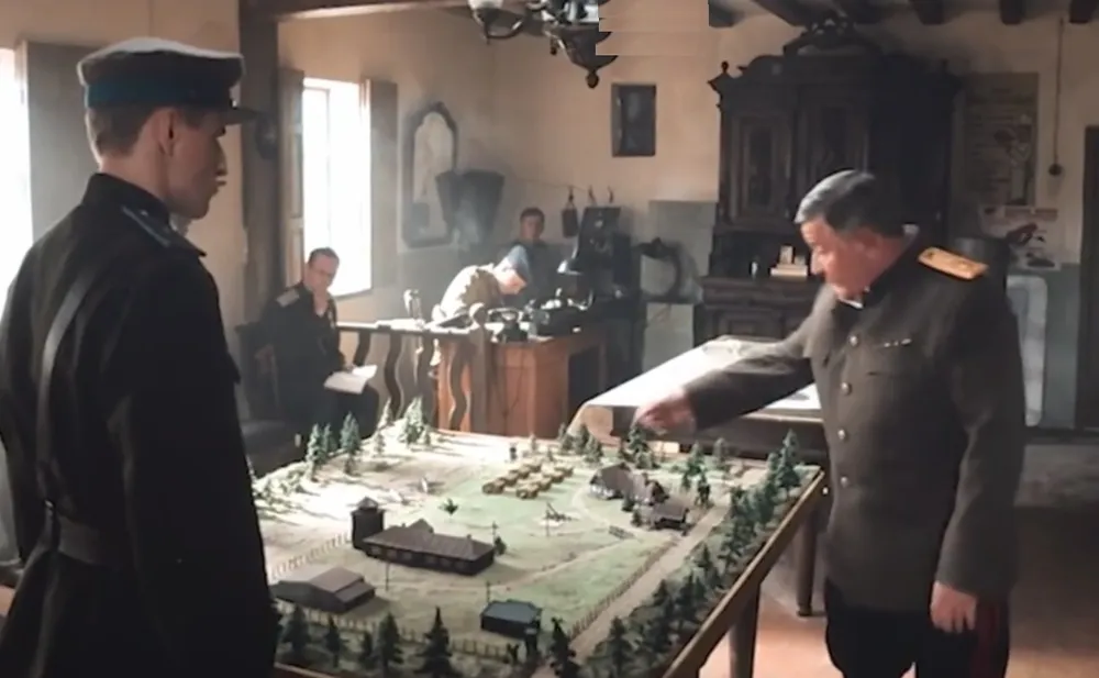 На картинке изображены мужчины в военной униформе, обсуждающие что-то на столе с макетом местности в военной обстановке.