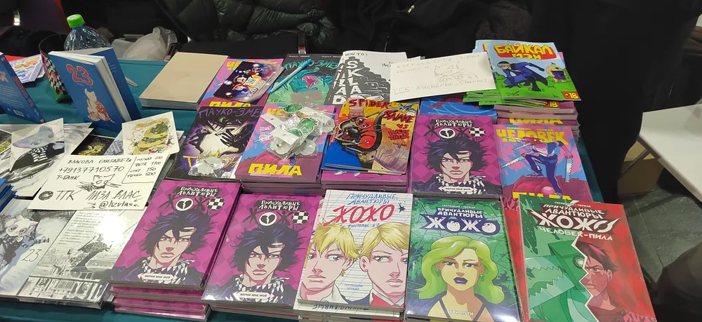 На изображении представлены комиксы и книги, разложенные на столе.