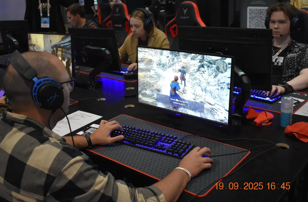 Изображение людей, играющих за компьютерами на игровом мероприятии.