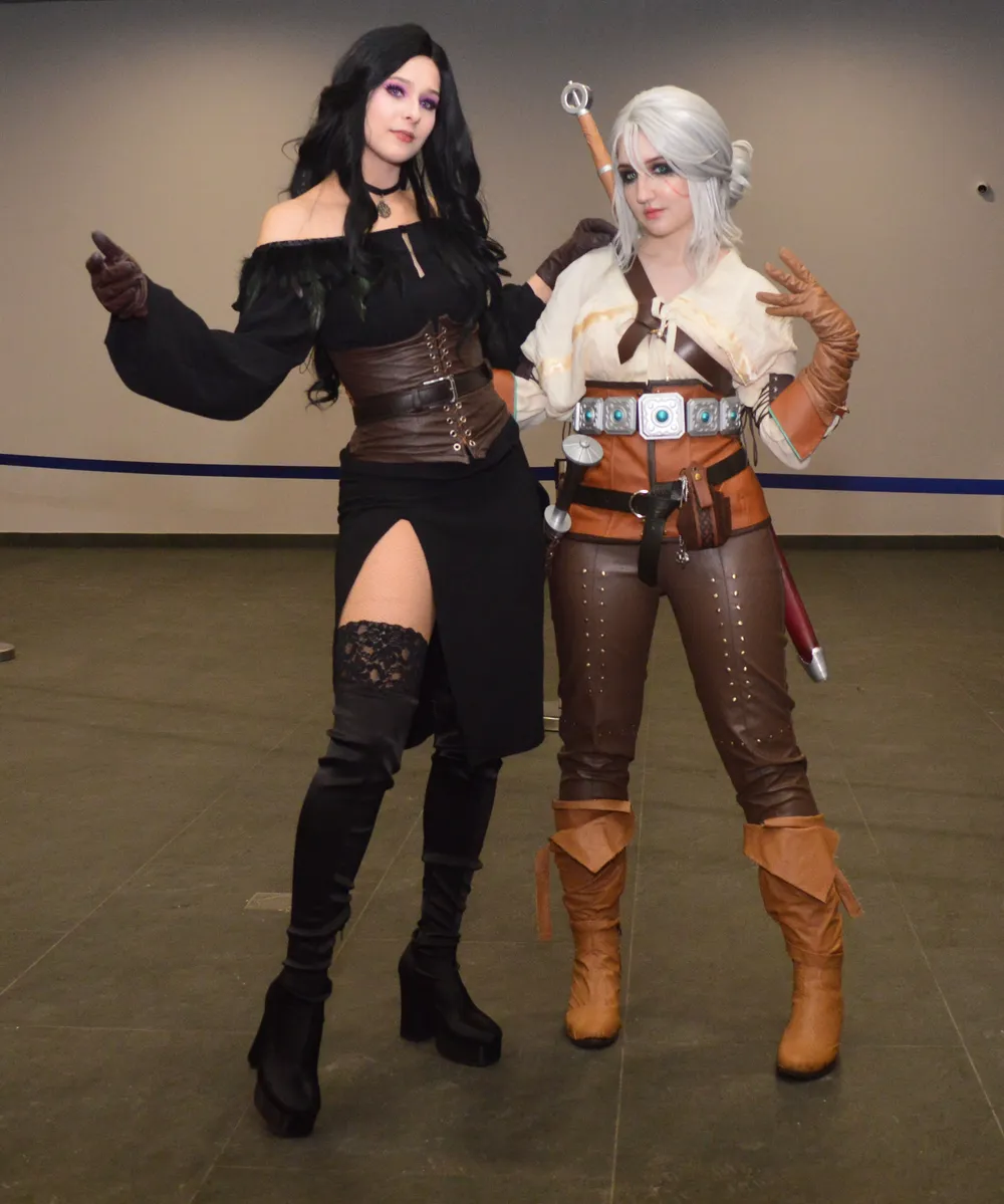 Две женщины в костюмах, одна в коротком платье и высоких ботфортах, другая в костюме с элементами фэнтези.