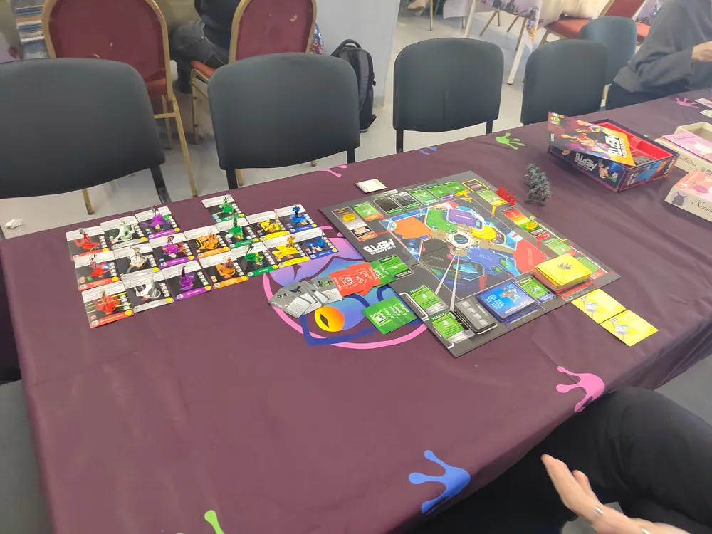 На изображении стол с настольными играми, карты и игровые предметы.