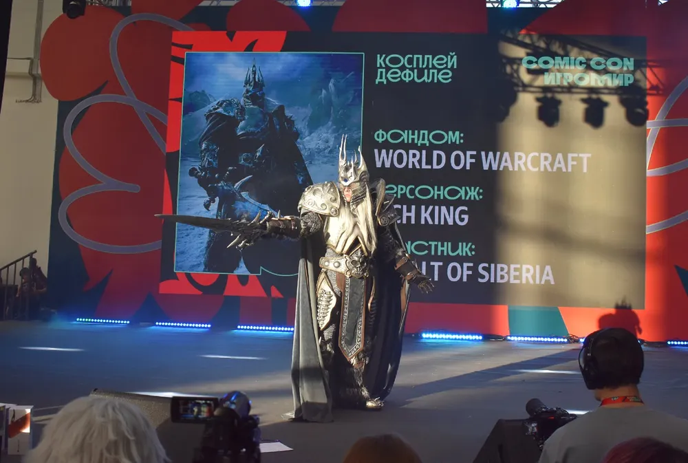 На изображении видно человека в костюме, который представляет персонажа из игры. Фон с названием мероприятия и изображением из игры.
