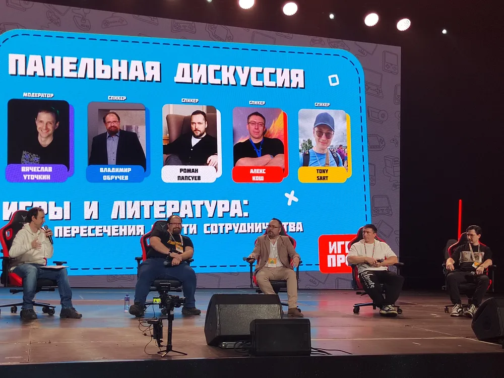 Изображение панельной дискуссии на сцене, участники обсуждают темы, связанные с играми и литературой. На экране видно название дискуссии и фотографии участников.