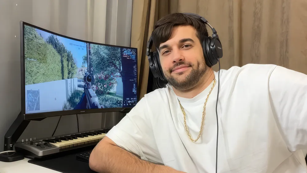 Изображение мужчины в наушниках, сидящего за компьютером с игровым экраном.