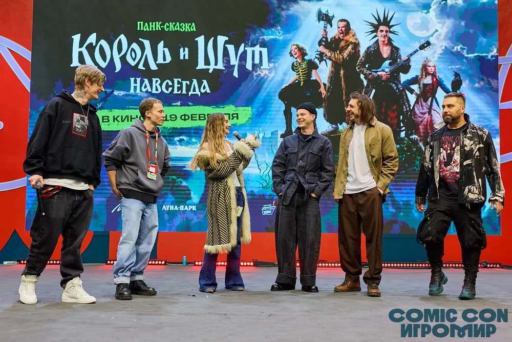 Группа людей на сцене на мероприятии, связанная с фильмом или шоу. На заднем плане баннер с названием \