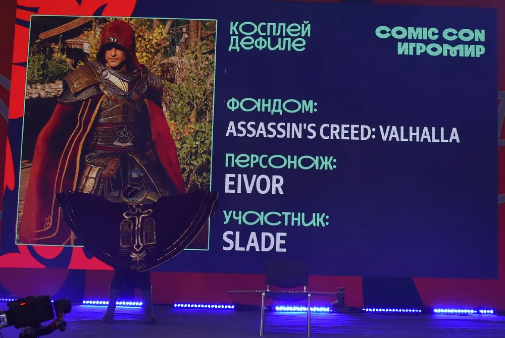 Изображение человека, одетого в костюм персонажа из игры. На экране представлена информация о фандоме, персонаже и участнике.