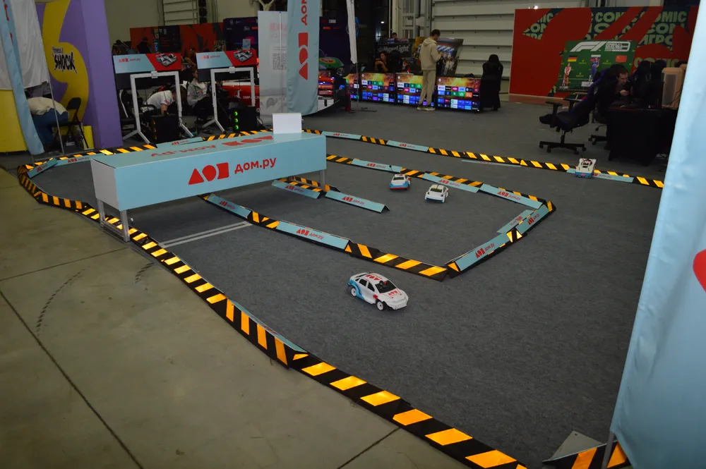 Изображение показывает трассу для радиоуправляемых машинок с разметкой и несколькими машинками на ней.