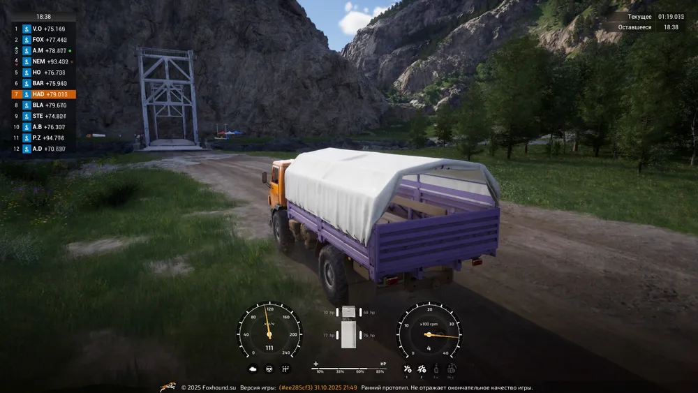 Изображение показывает грузовик на дороге в природном ландшафте, окружённом горами и деревьями.