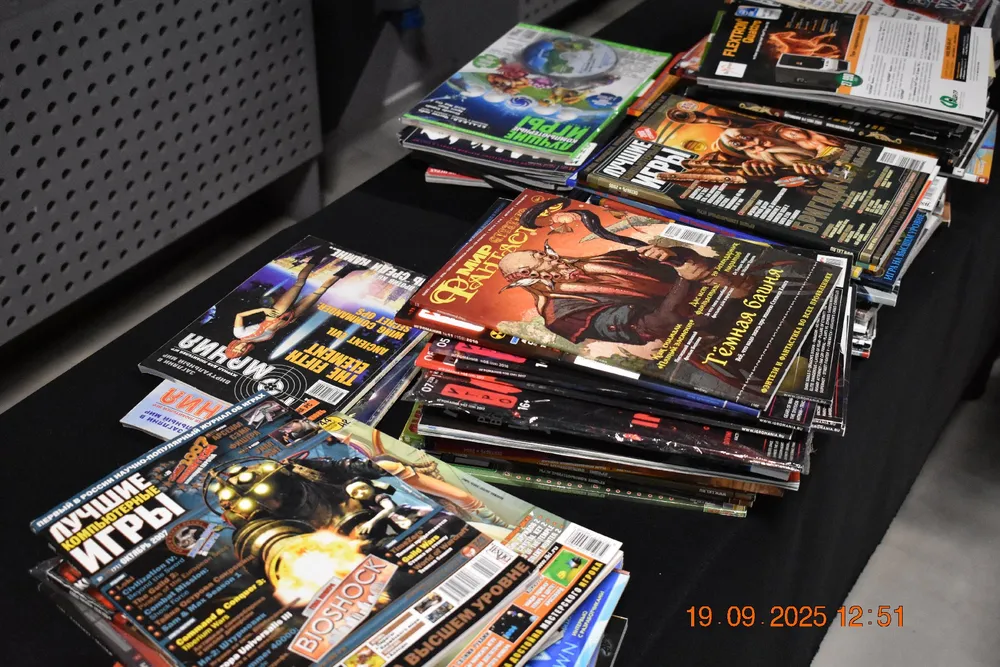 На изображении находятся журналы и книги, сложенные на столе. Видно разнообразие обложек с играми и тематикой развлечений.