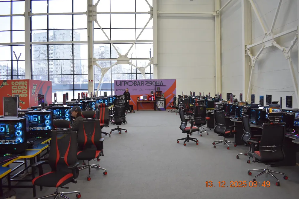 Изображение компьютерного клуба с рядами игровых компьютеров и кресел.