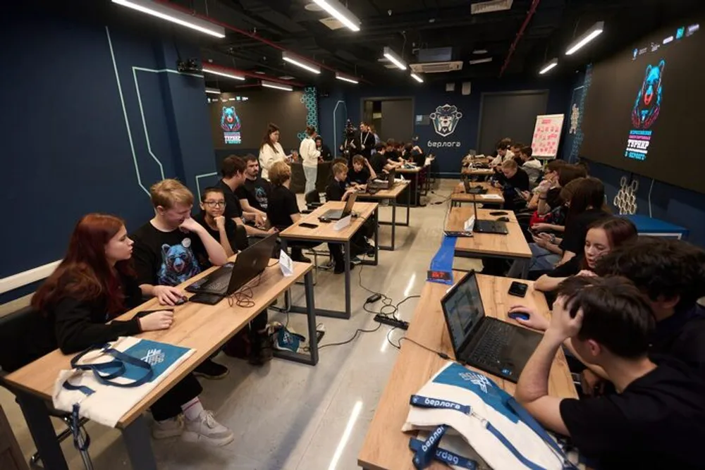 Изображение показывает группу людей, работающих за компьютерами в учебном помещении.