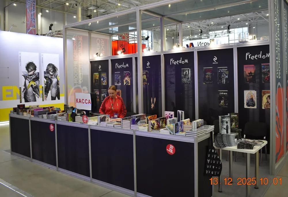 Изображение книжного стенда на выставке с женщиной за прилавком и книгами на витрине.