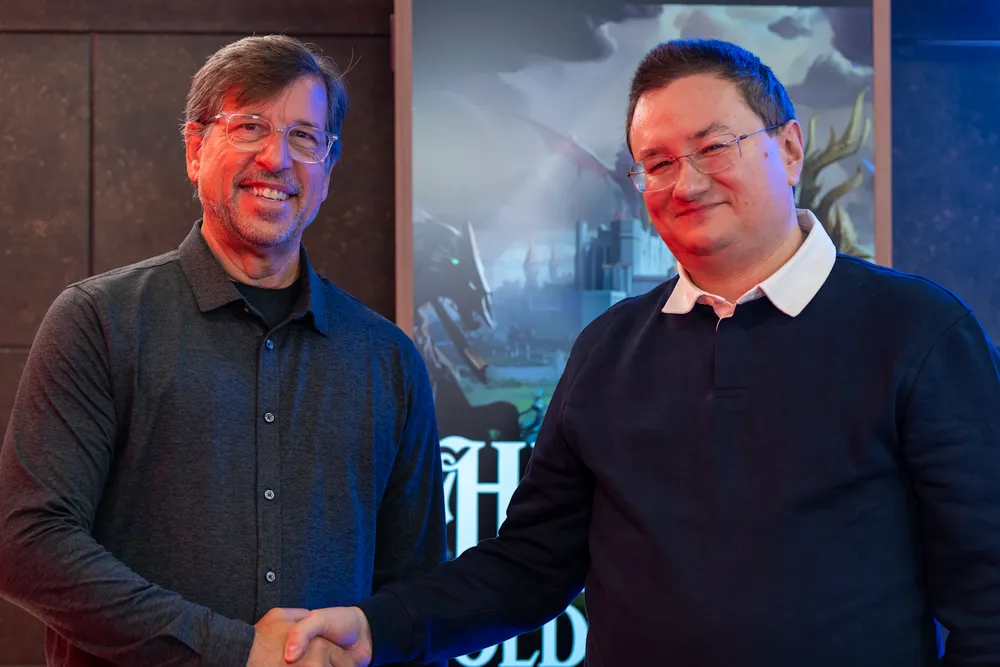 Два человека пожимают друг другу руки на фоне рекламного баннера.