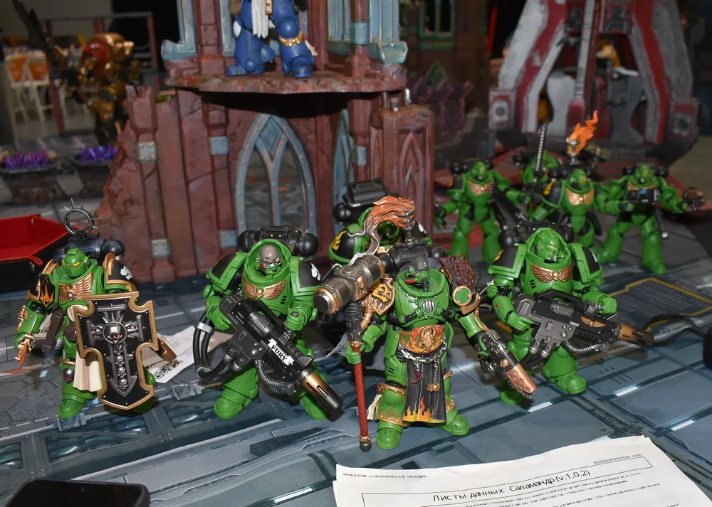 Изображение фигурок военных дронов или солдат в зеленой форме, расположенных на поверхности с игровой тематикой.