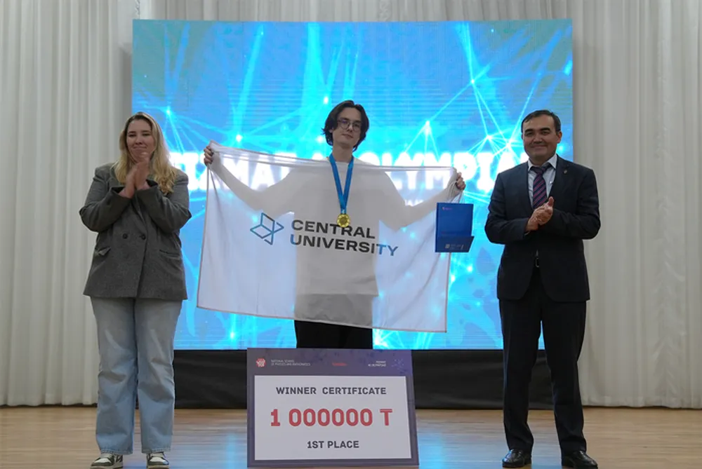 На изображении три человека на сцене, один из них держит знамя с надписью \