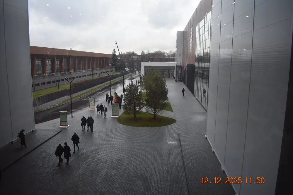 Изображение городской площади с людьми, зданиями и деревьями.