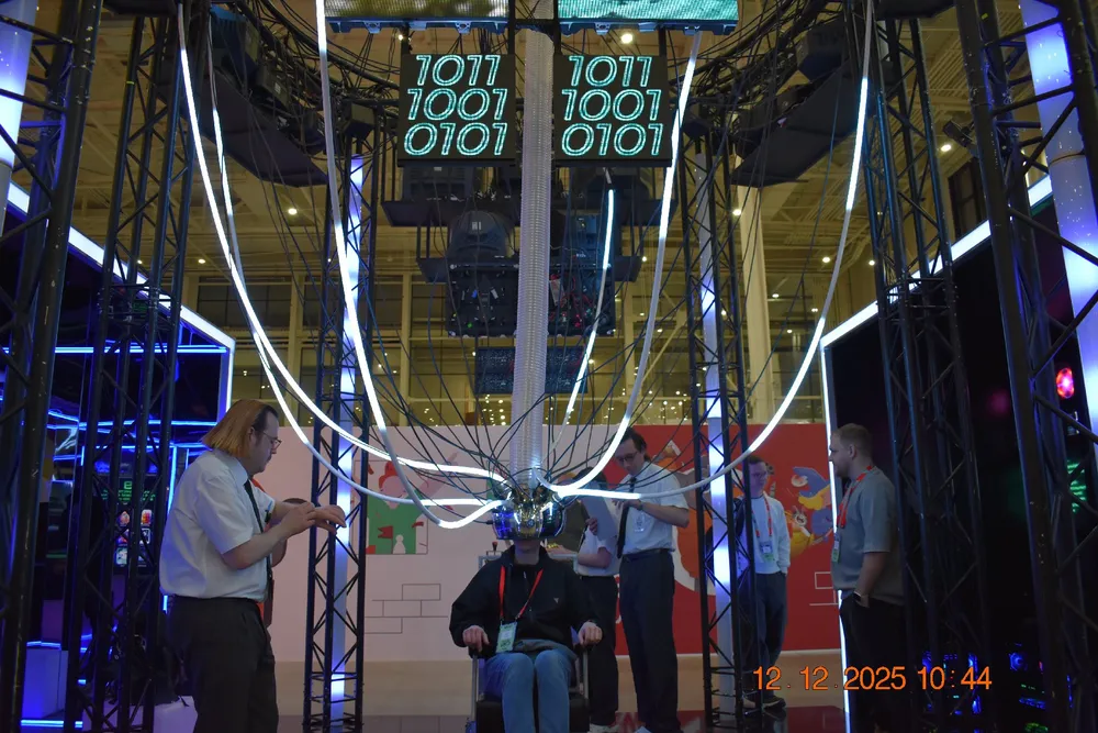 Изображение людей, взаимодействующих с технологическим оборудованием, возможно, на выставке или мероприятии. На заднем плане видны цифровые элементы.