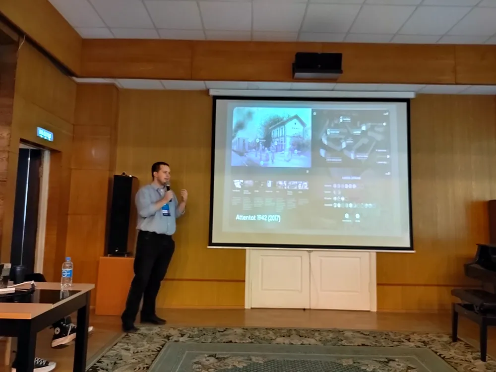 Мужчина на сцене, презентация с изображениями и текстом, аудитория, стена с деревянной отделкой