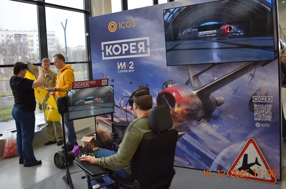 На изображении люди участвуют в мероприятии, есть реклама игры и игровая установка.