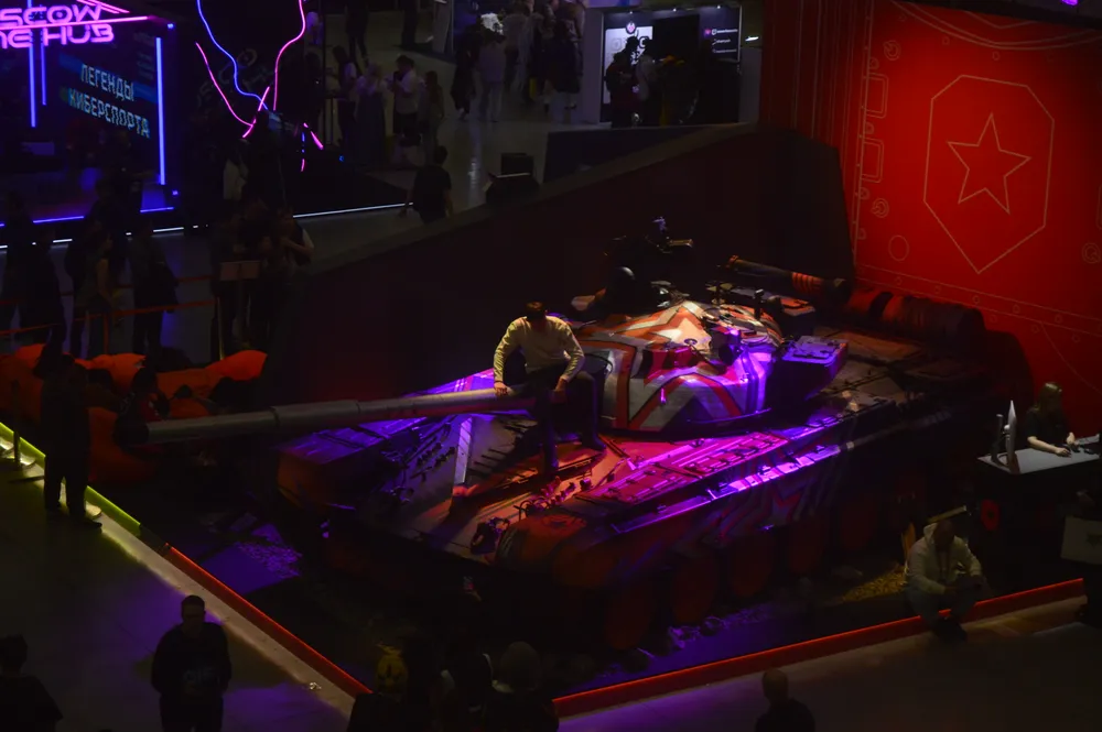 Изображение выставки с танком и людьми вокруг. Оборудование и элементы декора, присутствуют неидентифицированные люди.