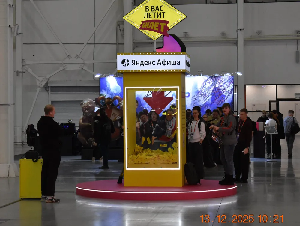 Изображение выставочного стенда с людьми, надписями и рекламой.