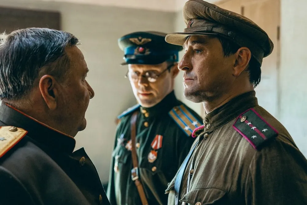 Трое мужчин в военной форме, обсуждают что-то между собой, возможно, на историческую тему.