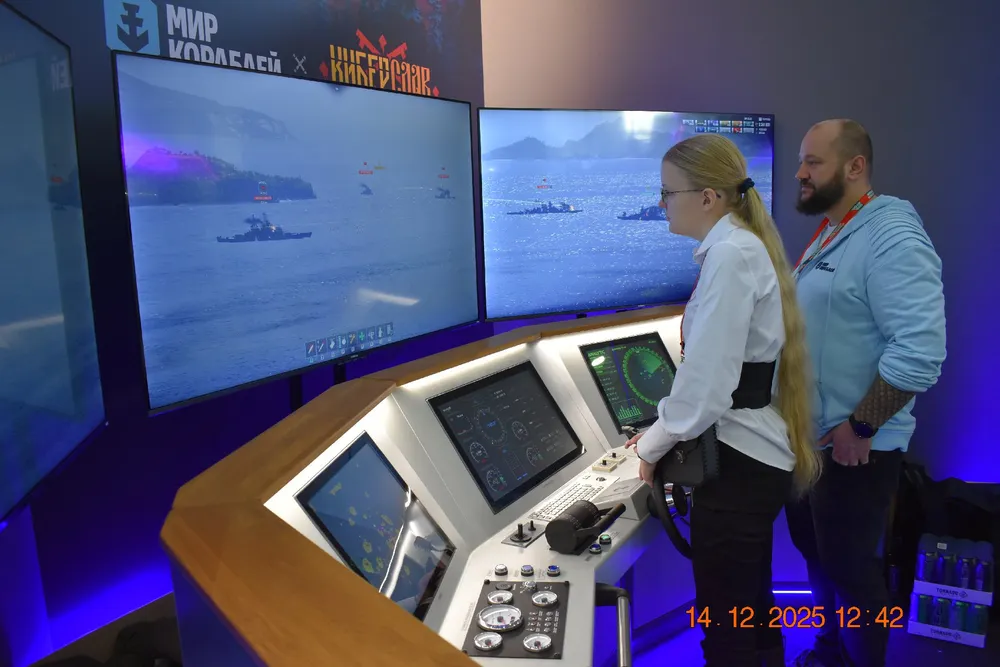 Два человека рядом с управленческой панелью и большими экранами, на которых отображается морская сцена.