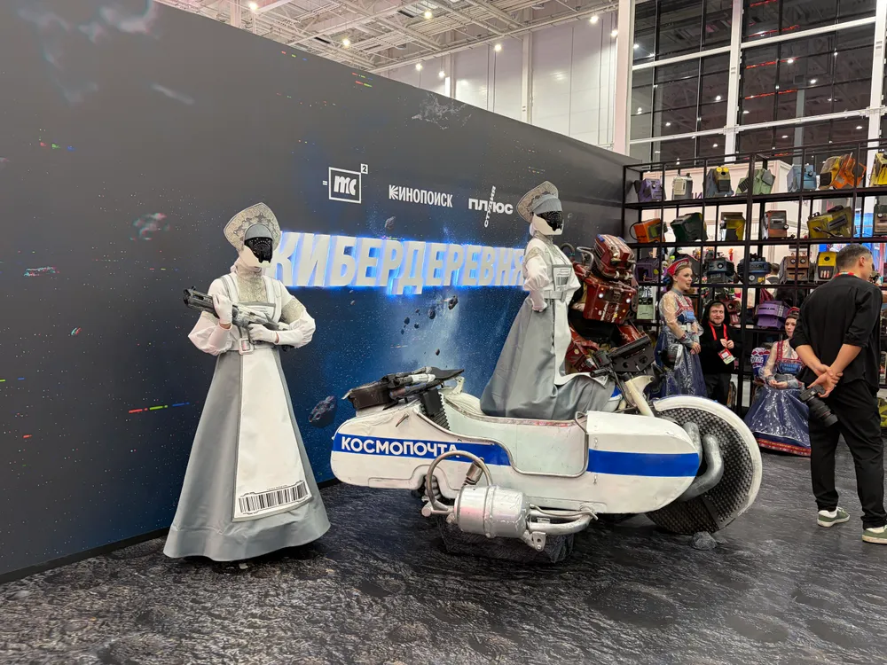 На изображении представлены люди в костюмах, а также мотоцикл. Фон с надписью \