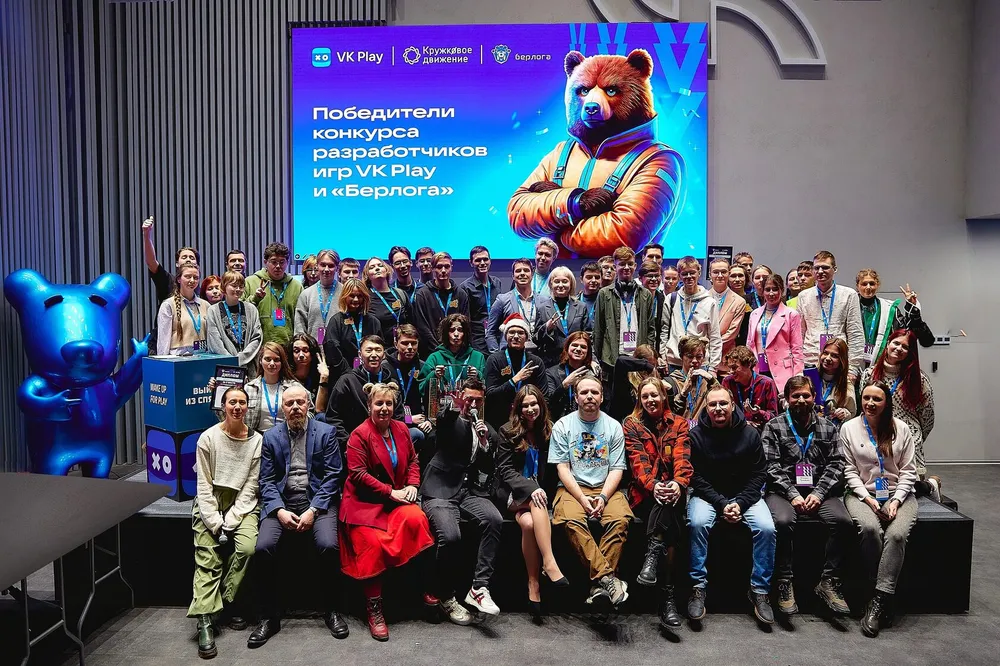 Группа людей на мероприятии, награждение победителей конкурса разработчиков, на заднем плане баннер с изображением медведя.